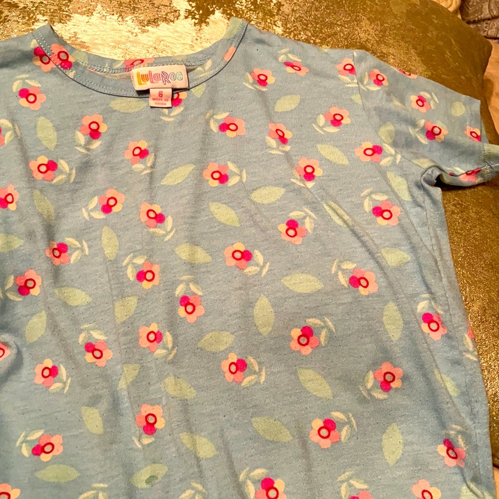 Short sleeve blue t-shirt with pink flowers. Shorter in front than back.